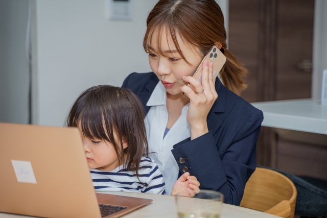 休日に子どもを見ながら仕事をするお母さん