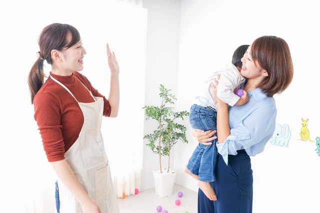 休日に保育士さんに子どもを預けるお母さん
